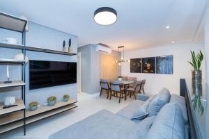 ein Wohnzimmer mit einem blauen Sofa und einem Esszimmer in der Unterkunft Adra 102 - Apartamento no centro de Bombinhas - Finamente mobiliado e decorado - Rooftop com piscina e academia - À poucos metros da praia in Bombinhas