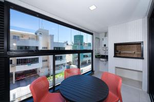 ein Esszimmer mit Tisch und Stühlen und einem großen Fenster in der Unterkunft Adra 102 - Apartamento no centro de Bombinhas - Finamente mobiliado e decorado - Rooftop com piscina e academia - À poucos metros da praia in Bombinhas