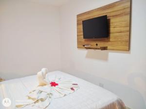 une chambre avec un lit avec une télévision au mur dans l'établissement Suites Areias de Porto, à Porto de Galinhas