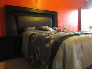 Cama en habitación roja con colcha y almohadas en Hotel Isabela, en San Carlos