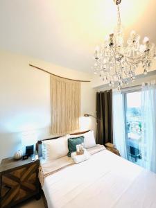 a bedroom with a large white bed and a chandelier at Davao Boutique Condos - Inspiria Abreeza in Davao City