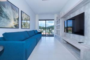 a living room with a blue couch and a tv at Adra 306 - Excelente Cobertura Duplex - Centro/Bombinhas- Rooftop com Piscina - À poucos metros da praia - (Consultar serviços de roupas de cama e banho) in Bombinhas