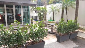 un patio con plantas, mesa y sillas en A1 Flats Radisson Berrini, en São Paulo