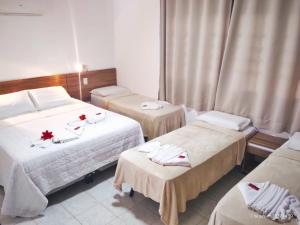 une chambre d'hôtel avec trois lits avec des serviettes dessus dans l'établissement Suites Areias de Porto, à Porto de Galinhas 17 autres photos