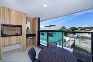 Zimmer mit einem Balkon mit Tisch und Stühlen in der Unterkunft Adra 103 - Apartamento no centro de Bombinhas - Rooftop com piscina e academia - À poucos metros da praia - (Consultar serviços de roupas de cama e banho) in Bombinhas