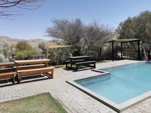 a swimming pool with two benches and a picnic table at Achab Self Catering Tent in Usakos