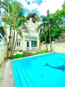 une grande piscine bleue en face d'une maison dans l'établissement Gem Villa 15, biệt thự 8 phòng ngủ lớn, hồ bơi lớn, à Hô-Chi-Minh-Ville