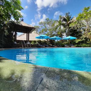 a swimming pool with umbrellas in a resort at Sama's Cottages and Villas in Ubud