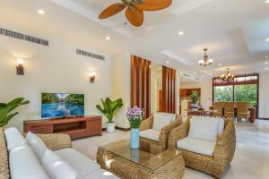 sala de estar con muebles blancos y ventilador de techo en Da Nang Paradise Center My Khe Beach Resort & Spa en Da Nang