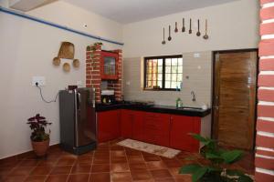 uma cozinha com armários vermelhos e um frigorífico preto em Shimmering View em Kalyānpur