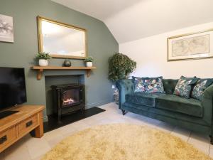 a living room with a green couch and a fireplace at The Talkhouse Cottage in Caersws