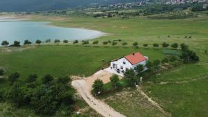 uma pequena casa branca num campo ao lado de um lago em Vikendica Bruše em Jaklići