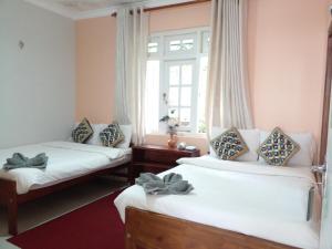 um quarto com duas camas e uma janela em Vibe way (Hostel & Market farm) em Nuwara Eliya