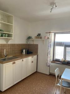 kuchnia z białymi szafkami, stołem i oknem w obiekcie Apartman Centrum w Jiczynie