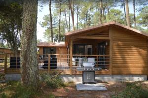 una cabaña de madera en el bosque con parrilla en Chalet 62 en Ondres