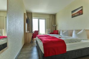 a hotel room with a large bed with a red blanket at Rügen-Hotel in Sassnitz
