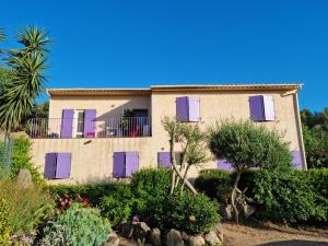 ein Gebäude mit lila Fensterläden und einem Garten in der Unterkunft L'ortu di Quaprice in Figari