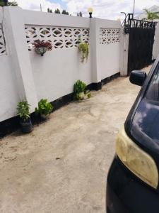 a car parked next to a white fence with potted plants at Mikocheni Home stay in Dar es Salaam