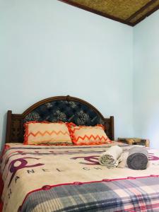 uma cama com um cobertor e almofadas em Sawe Homestay em Kuta