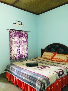 a bedroom with a bed with a blanket on it at Sawe Homestay in Kuta Lombok