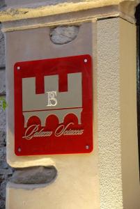 un panneau rouge sur le côté d'un bâtiment dans l'établissement Palazzo Sciacca, à Patti