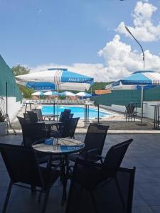 a group of tables and chairs with umbrellas and a pool at Restoran Mijajlovic in Kuršumlija