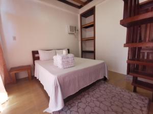 a bedroom with a bed with white sheets and a ladder at Latitude 10 Siargao in General Luna