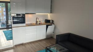 a kitchen with white cabinets and a couch in a room at Plac Unii: Rybka Premium in Gdynia