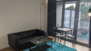 a living room with a black couch and a table at Plac Unii: Rybka Premium in Gdynia +11 photos