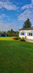 a house with a green lawn in front of a building at La clé des champs in Asnières