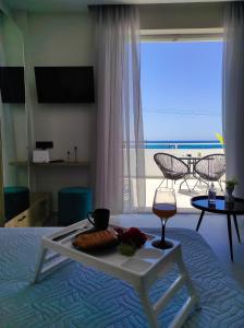 Bett mit einem Tablett mit Essen und einem Glas Wein in der Unterkunft Poseidonas luxury Apartment in Platanes