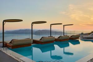 uma fila de camas sentadas em cima de uma piscina em Oia Suites em Oia