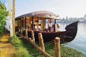 a boat sitting on the water next to a dock at Sreekrishna Houseboat in Kumarakom