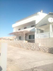 a white building with a stone wall and a building at Zdenka javoran in Zubovići
