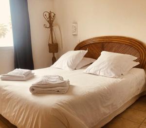 Una cama blanca con almohadas blancas y toallas. en Hôtel Lido Beach en Hyères