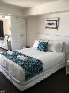 - une chambre avec un grand lit blanc et des oreillers bleus dans l'établissement Just Perfect Apartment with Ocean Views, à Caloundra