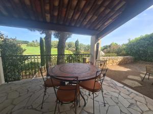 un patio con mesa y sillas en un porche en SUPERBE VILLA-DOMAINE AVEC GOLF PISCINE ET TENNIS en Saint-Cyr-sur-Mer