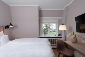 a bedroom with a white bed and a desk and a window at Benen-Diken-Hof in Keitum