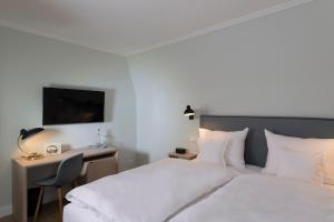 a bedroom with a bed and a desk and a television at Benen-Diken-Hof in Keitum