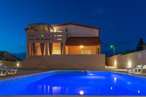 a swimming pool in front of a house at night at Apartmani Kržak in Nin