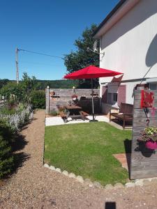 a patio with a table and a red umbrella at Le Terrier in Chamberet