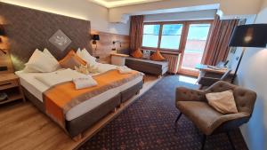 um quarto de hotel com uma cama grande e uma cadeira em Sport und Familienhotel Klausen em Kirchberg in Tirol