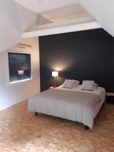 a bedroom with a large bed with a black wall at Les Tilleuls - Villa année 30 in Sancergues