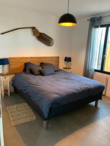 ein Schlafzimmer mit einem großen Bett mit einer Gitarre an der Wand in der Unterkunft Le moulin des sables, maison rétaise. in La Flotte