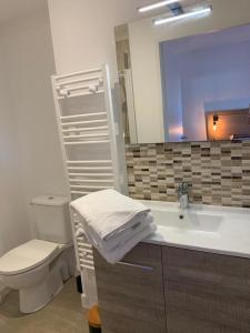 ein Badezimmer mit einem Waschbecken, einem WC und einem Spiegel in der Unterkunft Le moulin des sables, maison rétaise. in La Flotte
