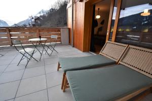 a patio with chairs and a table on a balcony at VAUJANYLOCATIONS - La Cabane de Maurice in Vaujany