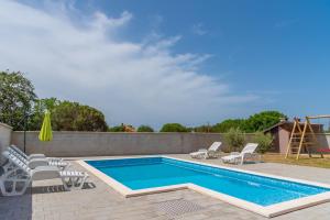 a swimming pool with chairs and a slide at Apartmani Kržak in Nin