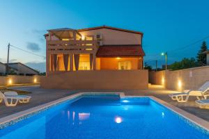 a villa with a swimming pool in front of a house at Apartmani Kržak in Nin