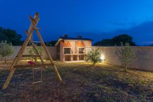 a wooden swing in a yard with a house in the background at Apartmani Kržak in Nin