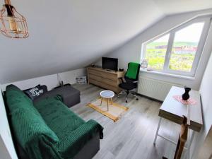 uma sala de estar com um sofá verde e uma janela em Quiet and Cozy 2 bedroom flat with free parking included em Floresti